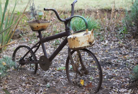 Chaise de jardin en plastique cassée avec assise fêlée, outils et matériaux de récupération à proximité
