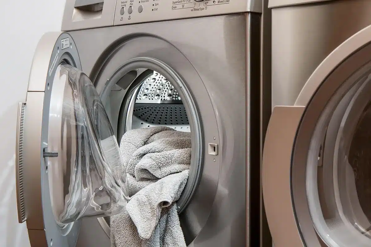 Main déposant une feuille de lessive dans le tambour d'une machine