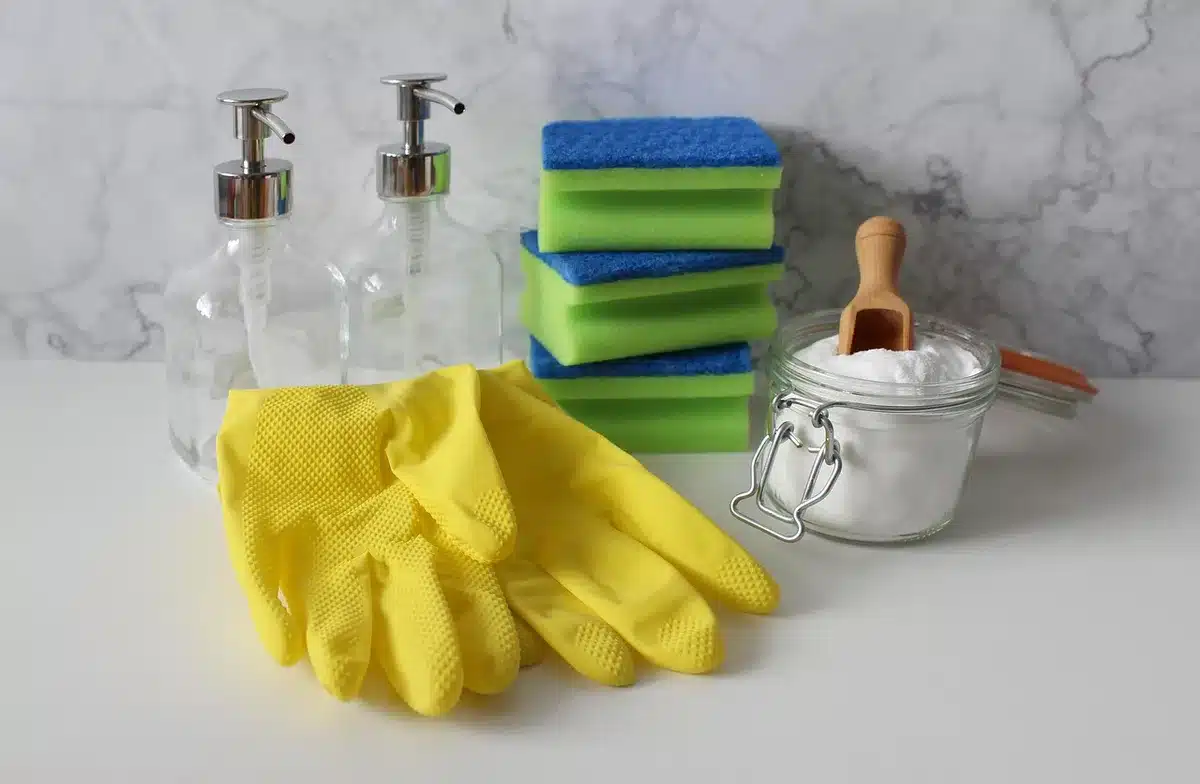 Main avec vaporisateur et brosse nettoyant une grille froide en plein jour